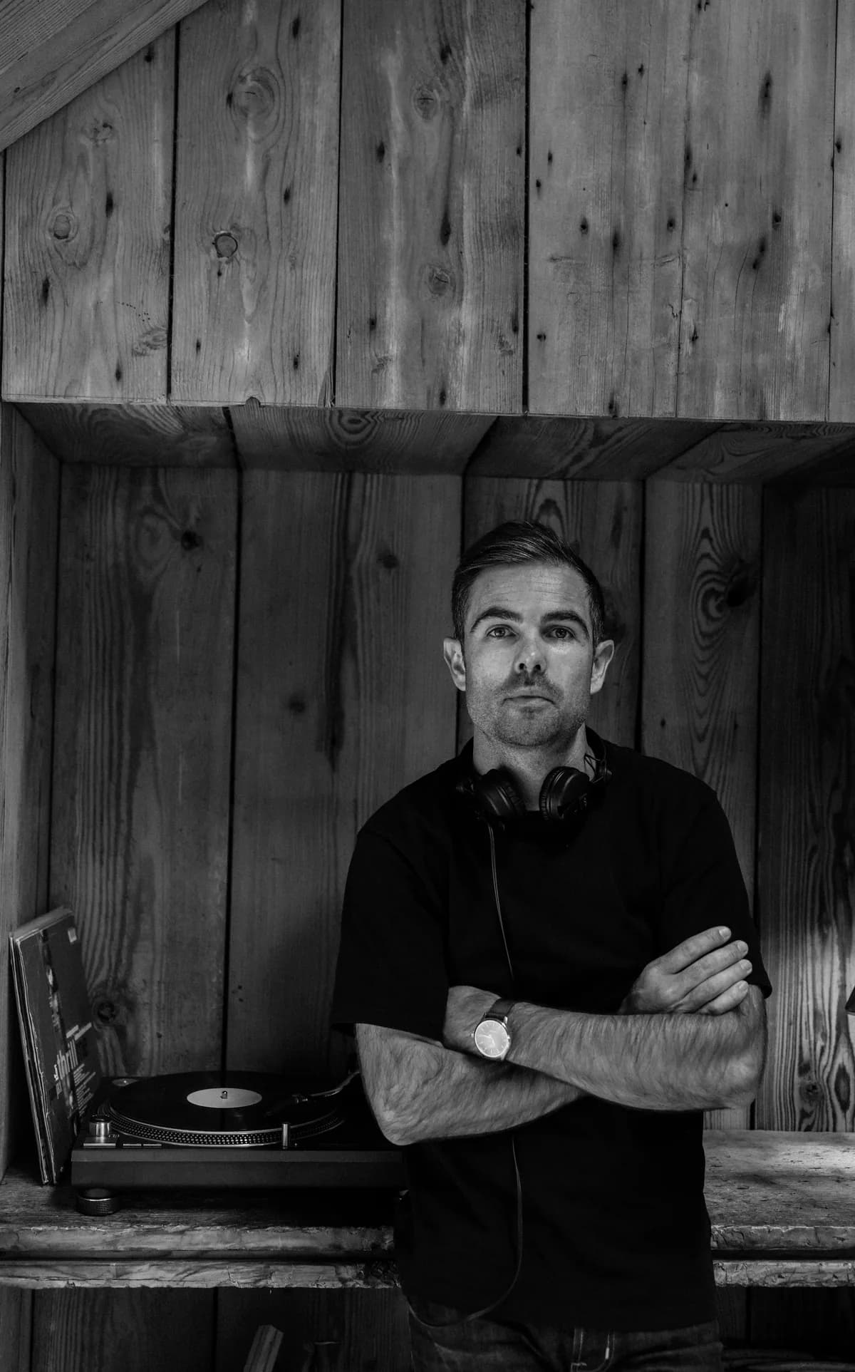 DJ Flo Shot, DJ in the network, in a black and white portrait beside a turntable