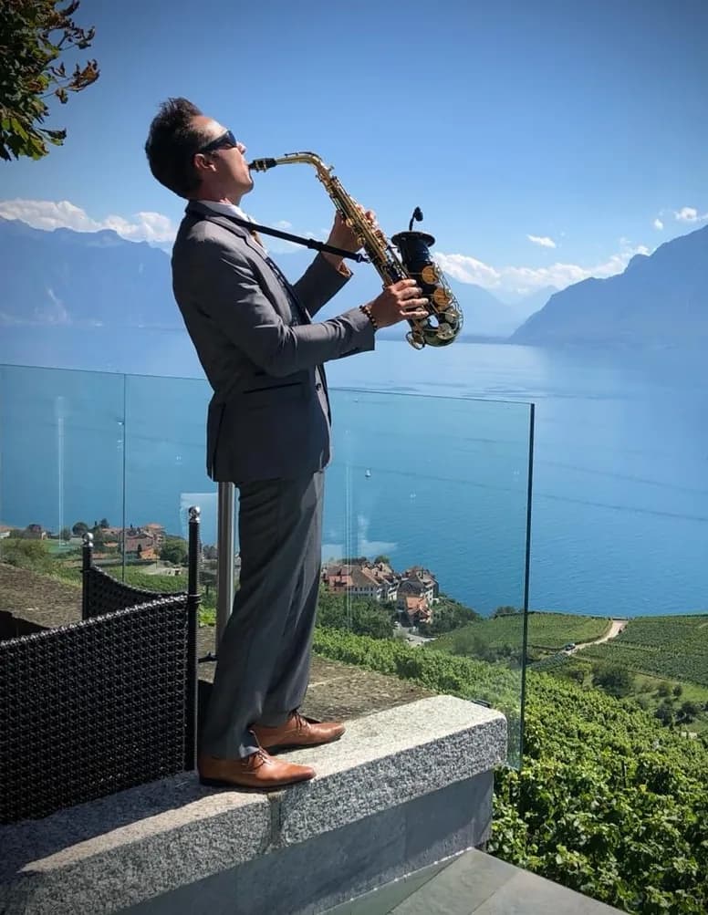 Julien, saxophoniste du réseau Be With You Events, jouant sur une terrasse face au lac
