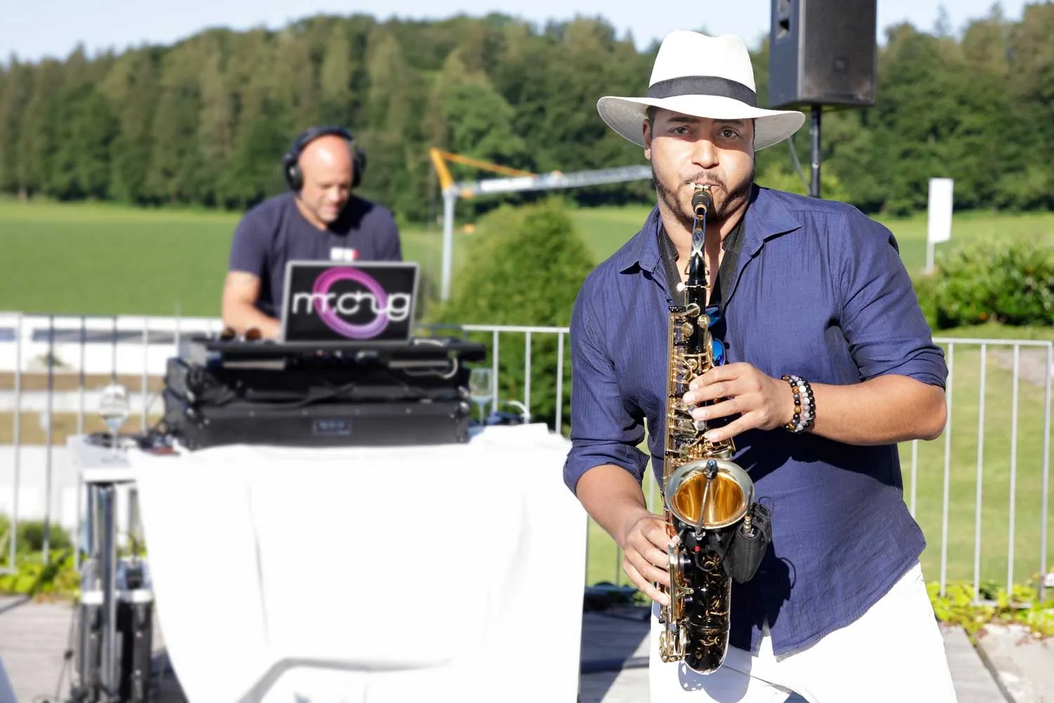 Saxophoniste au chapeau panama et DJ aux platines lors d'une réception en plein air