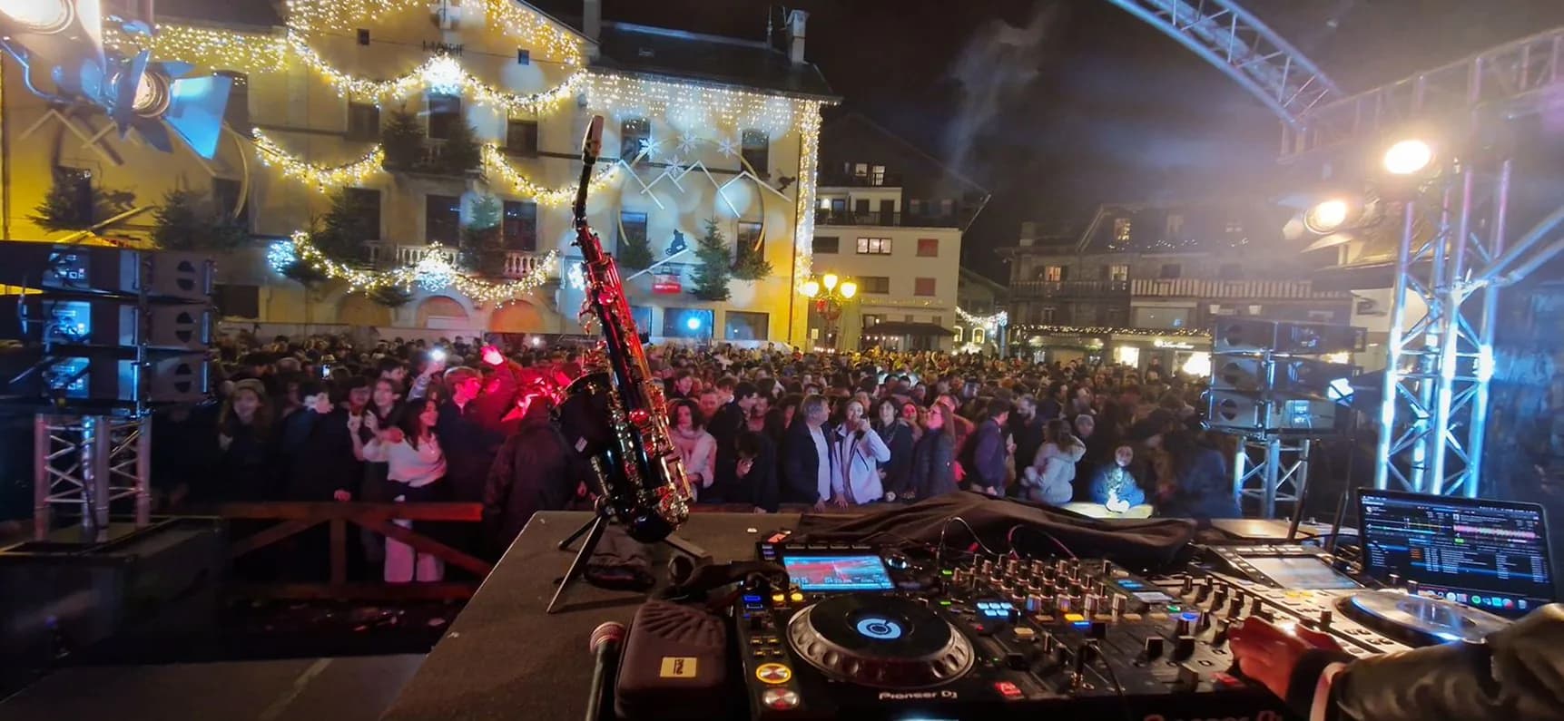 DJ aux platines face à une place de village bondée, soirée en France voisine