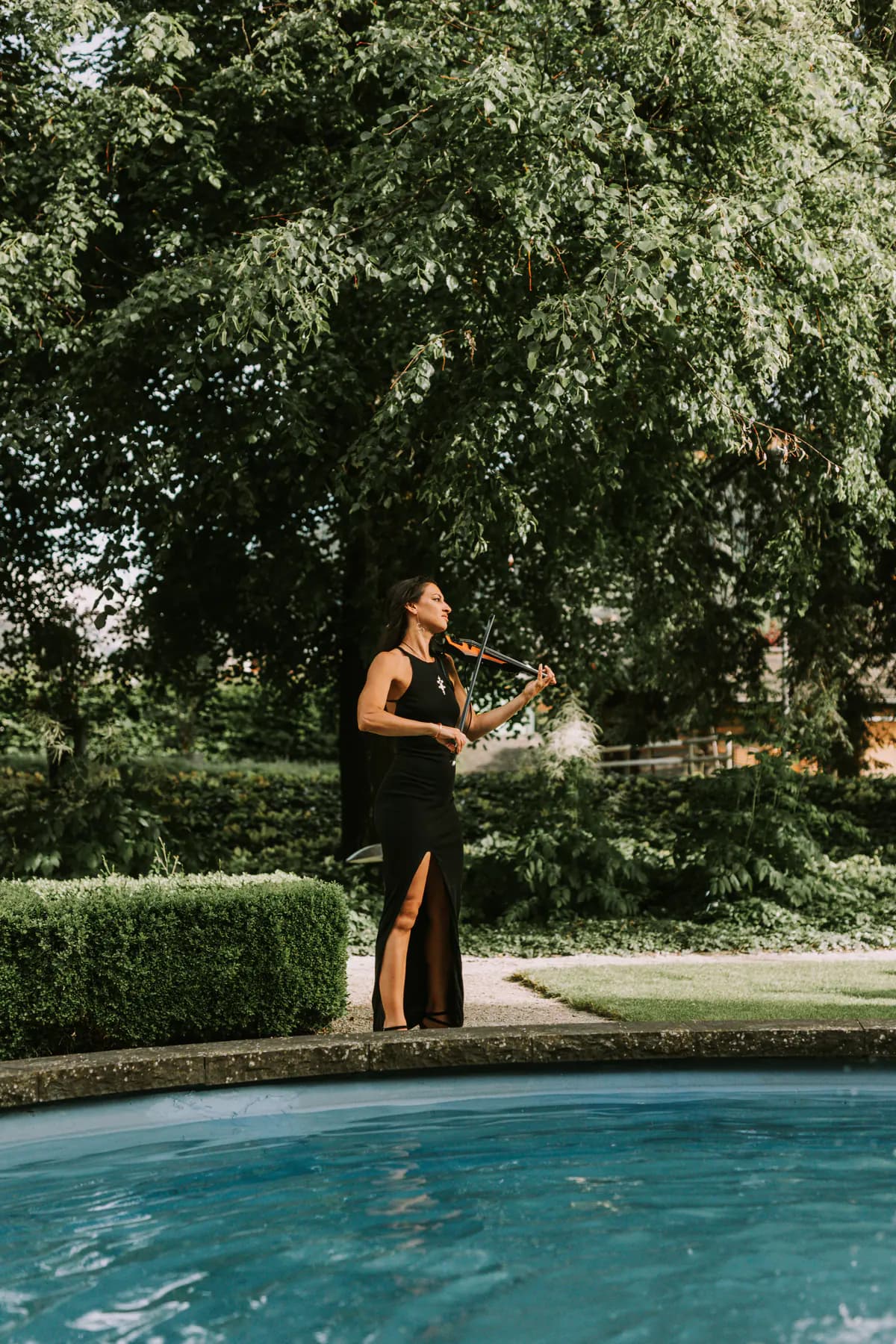 Margaux Malya, violoniste, jouant au bord d'un bassin dans le parc d'un hôtel
