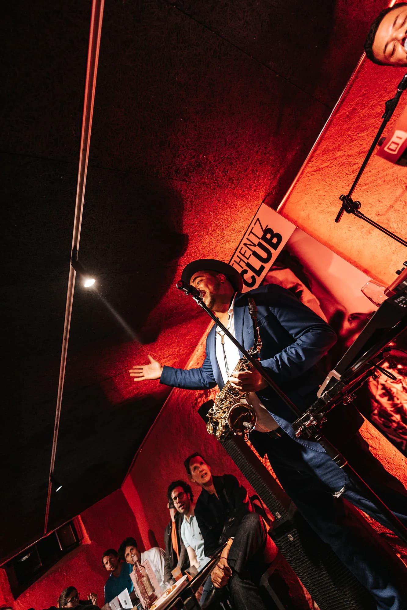 Saxophoniste bras ouverts sur la scène d'un club, dans la lumière rouge